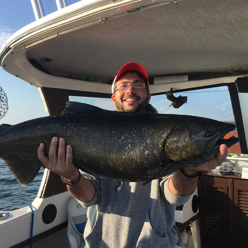 man smiling and holding a huge black fish on a boat